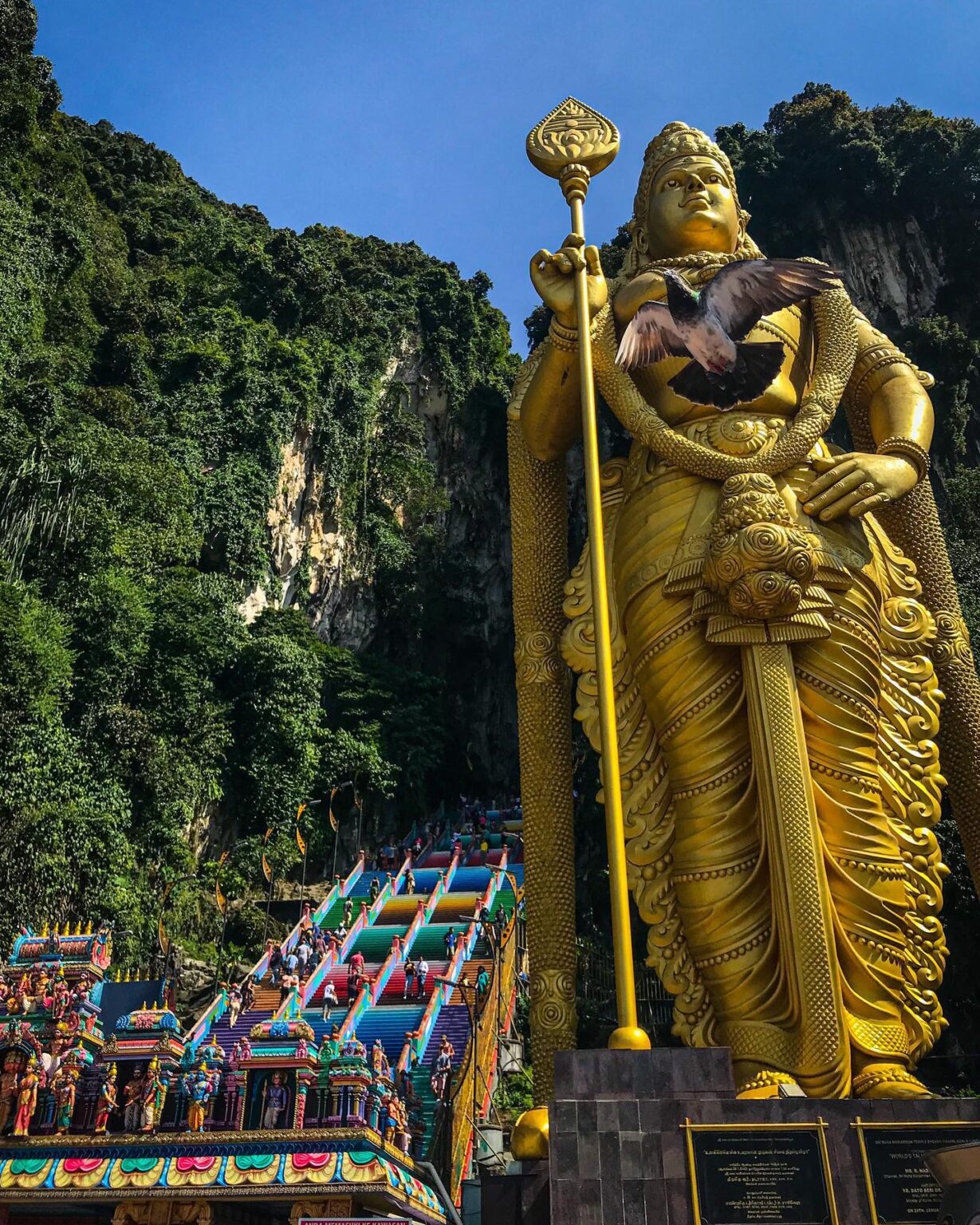 A bird passing by the statue of Kartikeya in Batu Caves. Kuala Lumpur, Malaysia