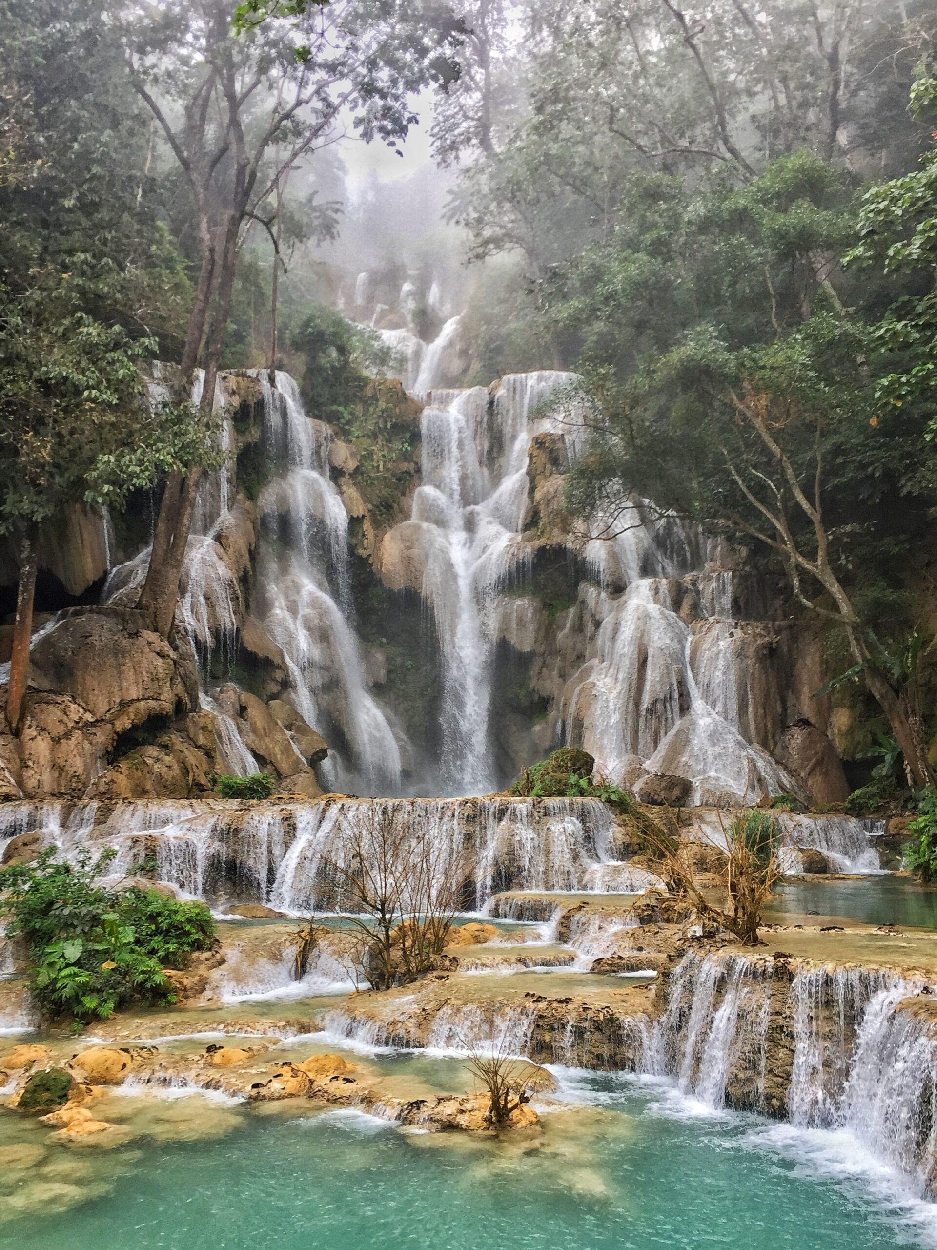 A breathtaking view of majestic Kuang Si waterfalls cascading down lush green mountains in Laos